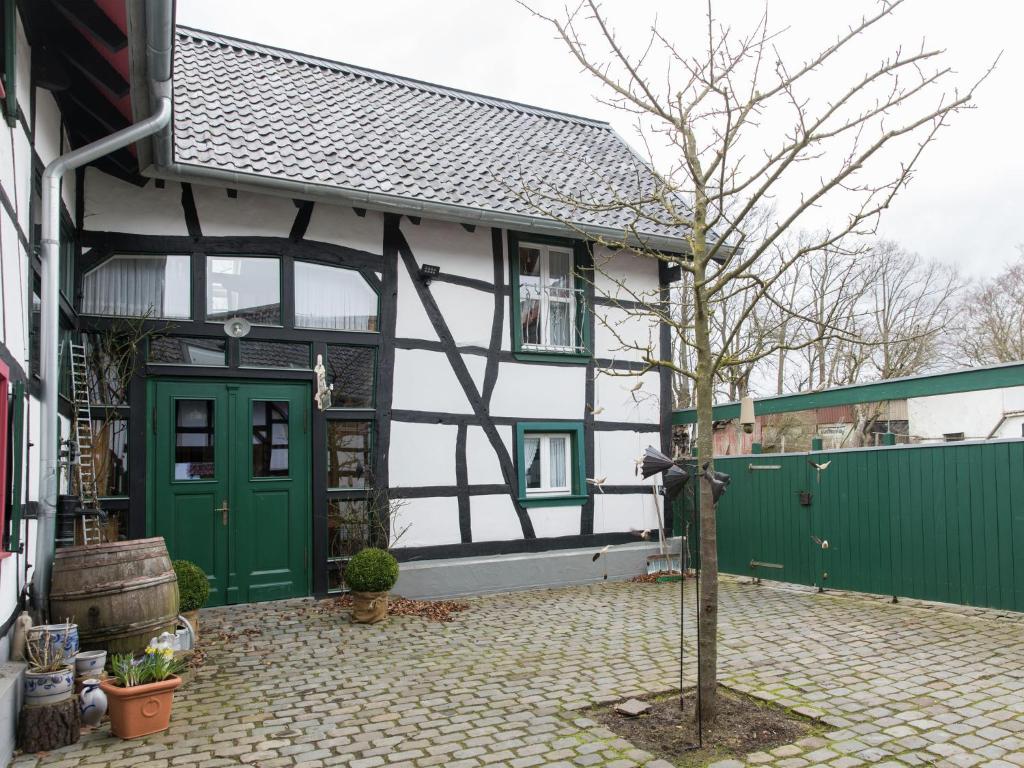 a house with green doors and a tree in the courtyard at Vintage Apartment with Garden in Schleiden