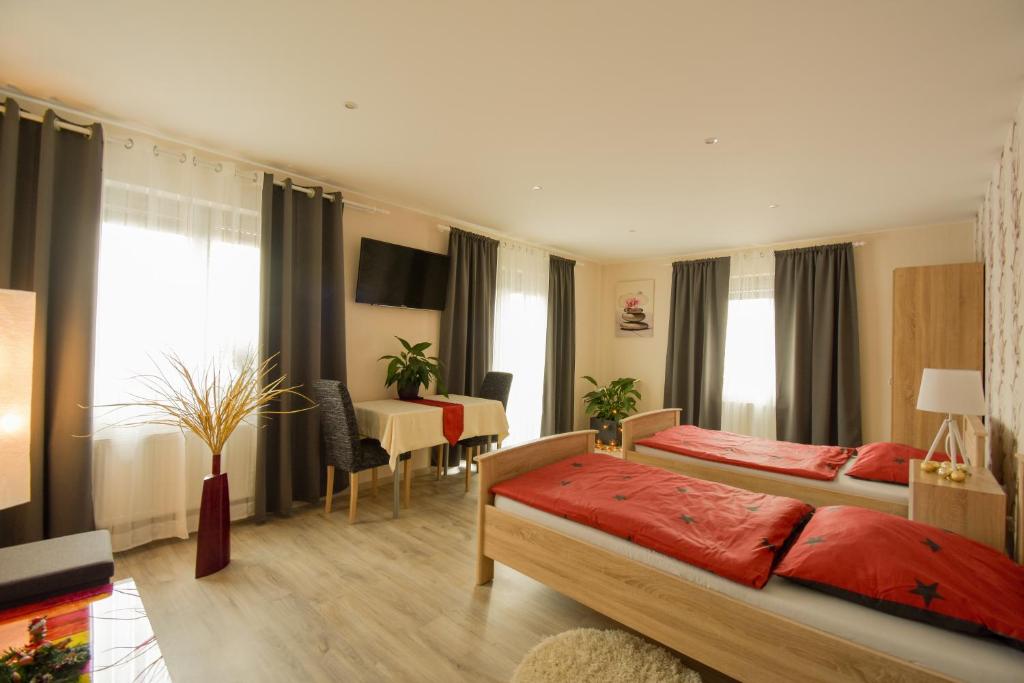 a bedroom with two beds and a table and a desk at Mainzimmer - Business Apartments in Hasloch