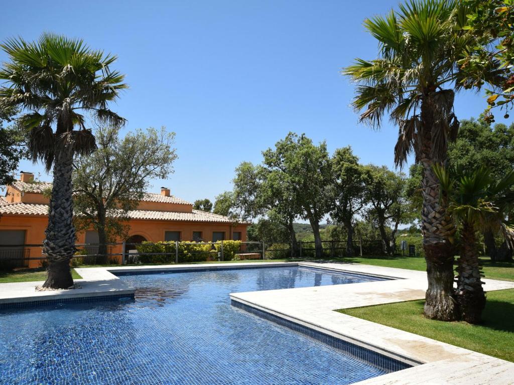 - une piscine bordée de palmiers en face d'une maison dans l'établissement Belvilla by OYO Mirador Mas Nou, à Castillo de Aro