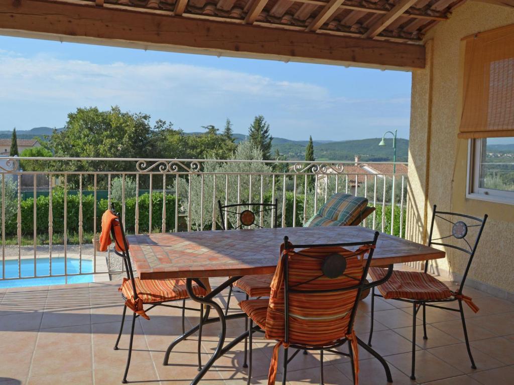 CornillonにあるVilla with swimming pool and valley viewの木製テーブルと椅子、プール付きのパティオ