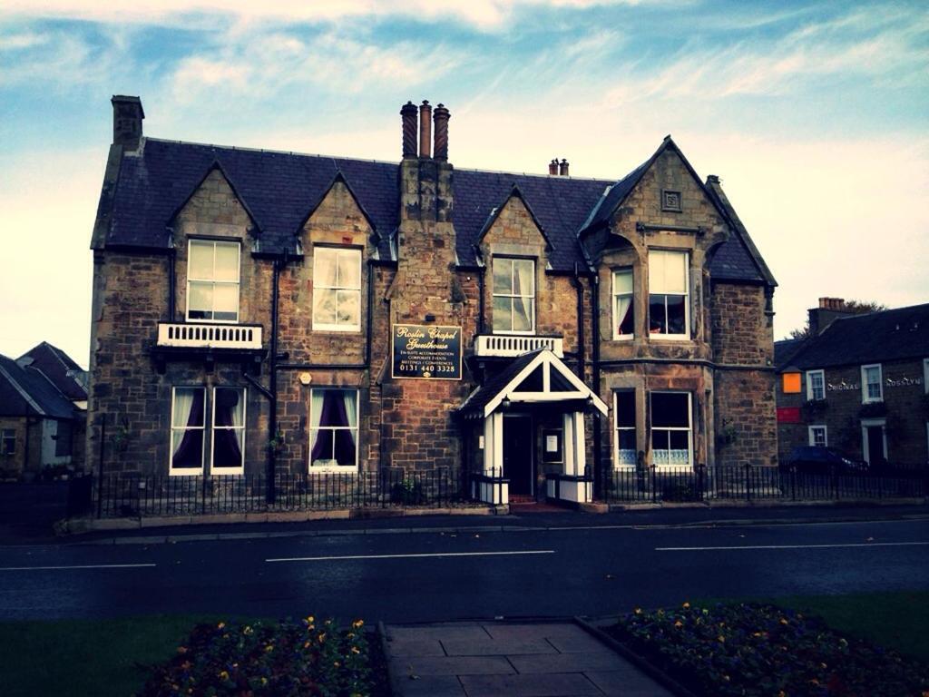 un viejo edificio de ladrillo con un cartel delante en Chapel Cross Guesthouse en Roslin