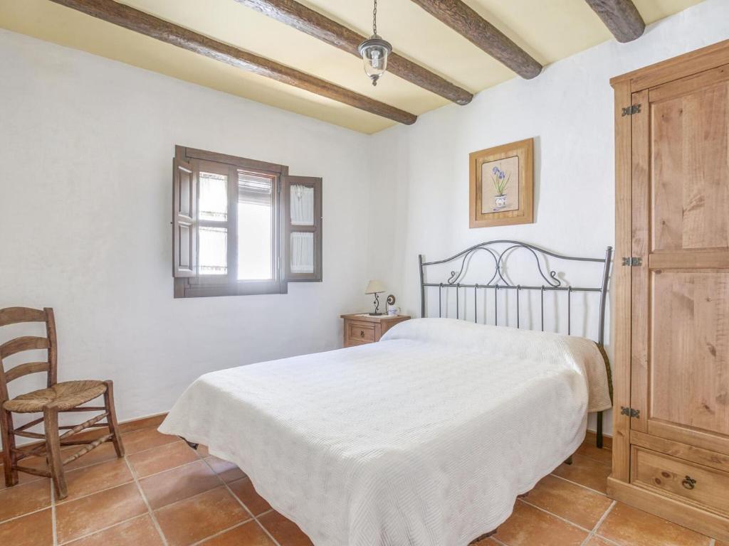 sypialnia z białym łóżkiem i krzesłem w obiekcie Villa in Carcabuey near Sierras Subbeticas Park w mieście Carcabuey