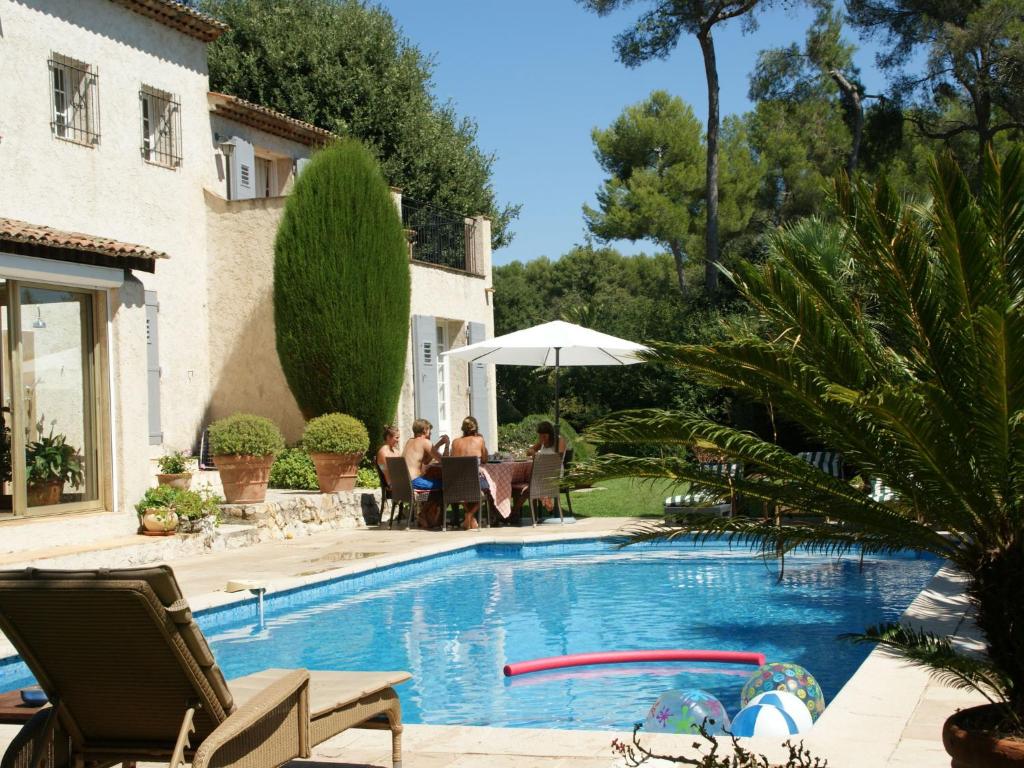 - une piscine avec des personnes assises autour d'une table à côté d'une maison dans l'établissement Villa in Saint-Paul-de-Vence with Pool Views, à Saint-Paul-de-Vence