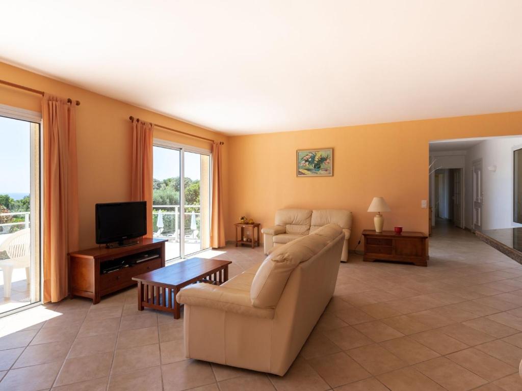 a living room with a couch and a tv at Modern villa with private pool in Santʼ Andrea-dʼOrcino