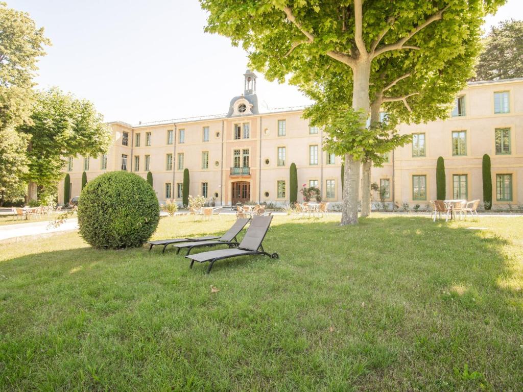 a building with two park benches in front of it at Studio in Montbrun Castle with Pool in Montbrun-les-Bains