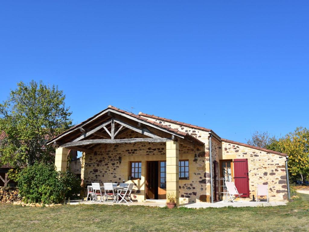 Saint-Avit-RivièreにあるLuxury house in Aquitaine with swimming poolの赤いドアとパティオ付きの石造りの家