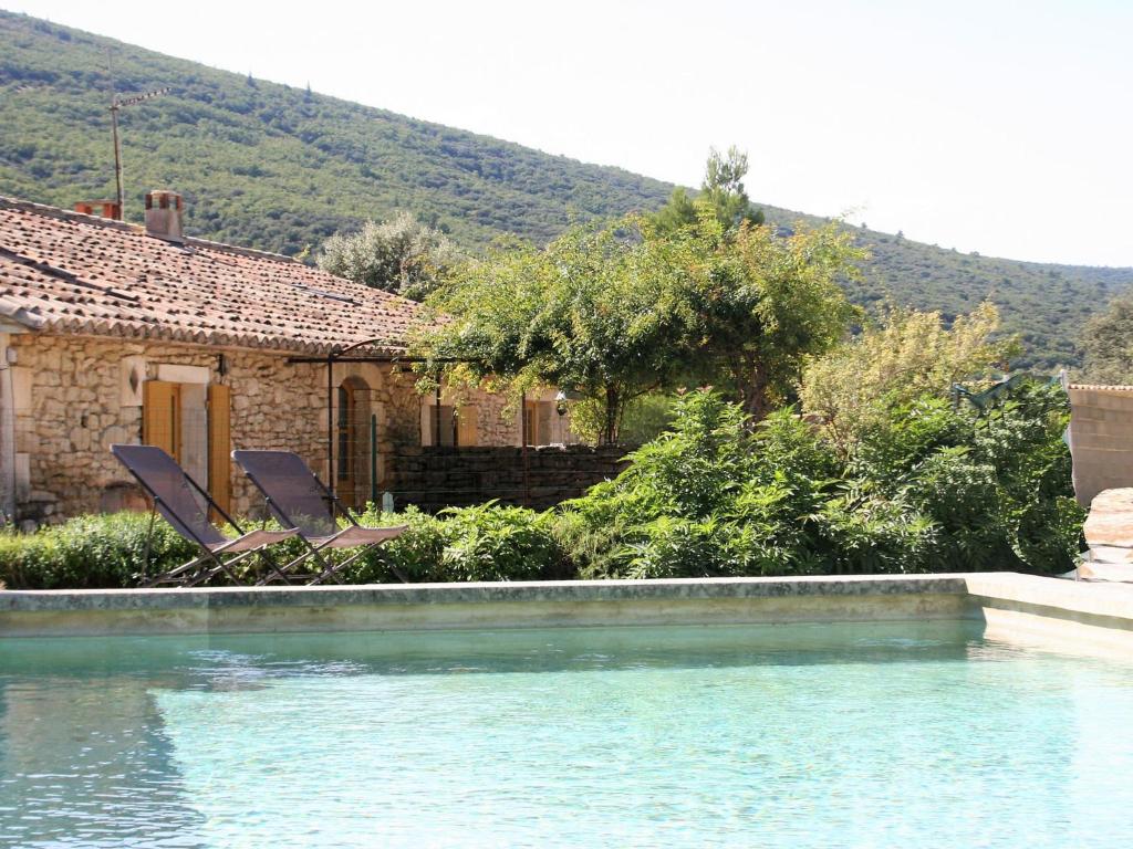 une maison avec deux chaises à côté d'une piscine dans l'établissement Stylish house with heated pool in Lacoste, à Lacoste