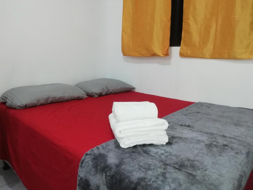 a bedroom with a red bed with towels on it at Pinares de Tecla in Nueva San Salvador