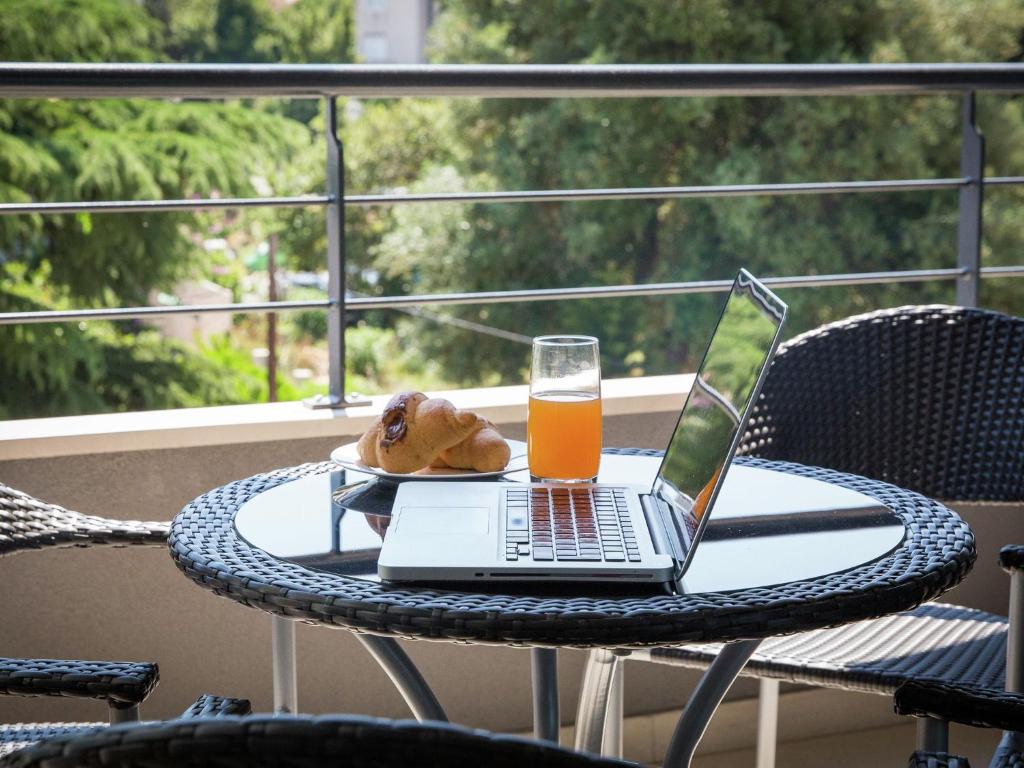 een tafel met een laptop en een glas sinaasappelsap bij Topfloor comfortable luxury apartment in Dubrovnik