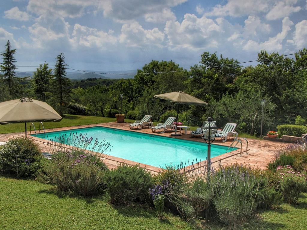 a swimming pool with chairs and umbrellas in a yard at Belvilla by OYO Villa La Palazzeta in Ficulle