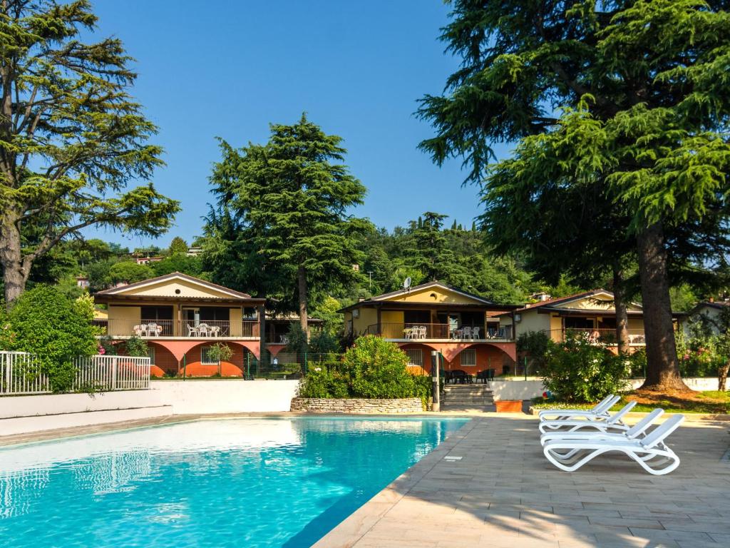 MontinelleにあるSerene Apartment in Manerba del Garda with Poolの白い椅子2脚付きのスイミングプールを利用できます。