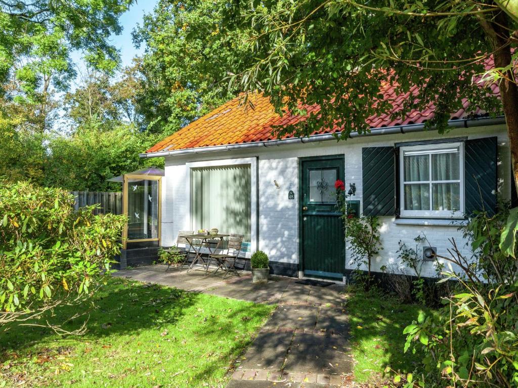 Ce cottage blanc dispose d'une porte verte et d'une terrasse. dans l'établissement Cozy Holiday home in Koudekerke Zealand, à Dishoek