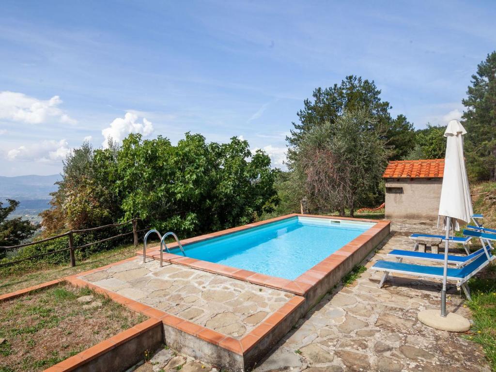 a swimming pool with two chairs and an umbrella at Belvilla by OYO Flat in farmhouse with pool in Pian di Scò