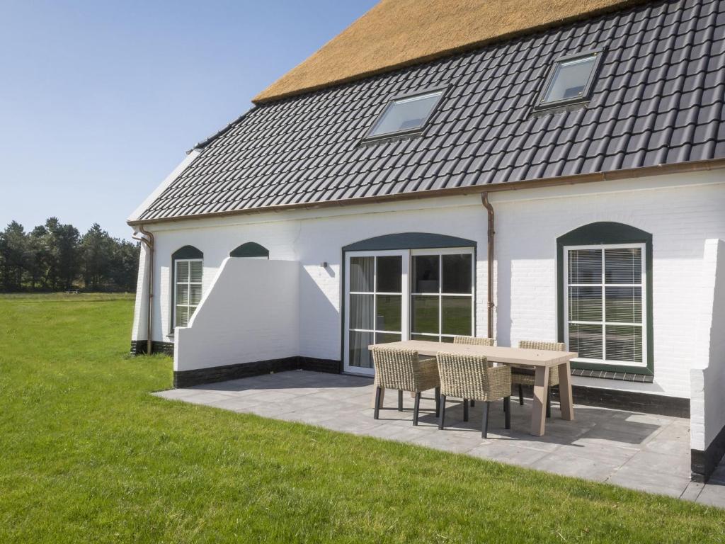 a picnic table in front of a white building at Apartment in tasteful farmhouse in De Cocksdorp in De Cocksdorp