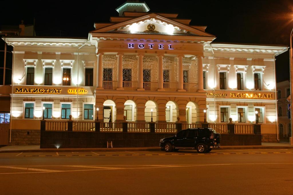 a building with a car parked in front of it at Magistrat Hotel in Tomsk