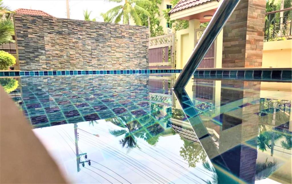 a swimming pool with a reflection of a house at Nasa Hotel in Phuket