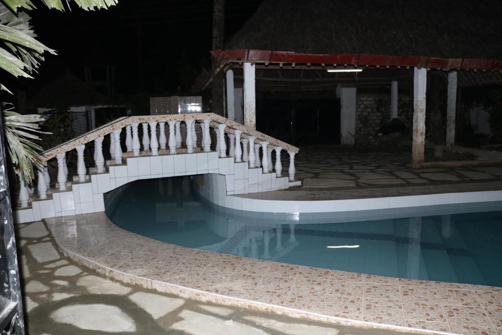 un puente de madera sobre una piscina por la noche en Room in Guest room - A wonderful Beach property in Diani Beach Kenya en Mombasa