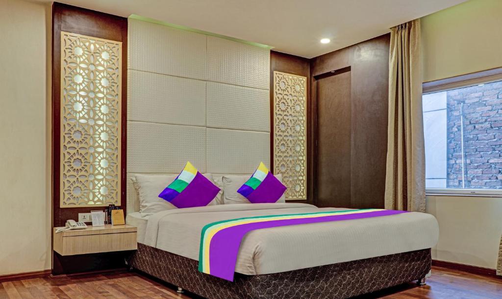 The Onyx Hotel في جمشيدبور: غرفة نوم مع سرير كبير مع وسائد وردية وأرجوانية