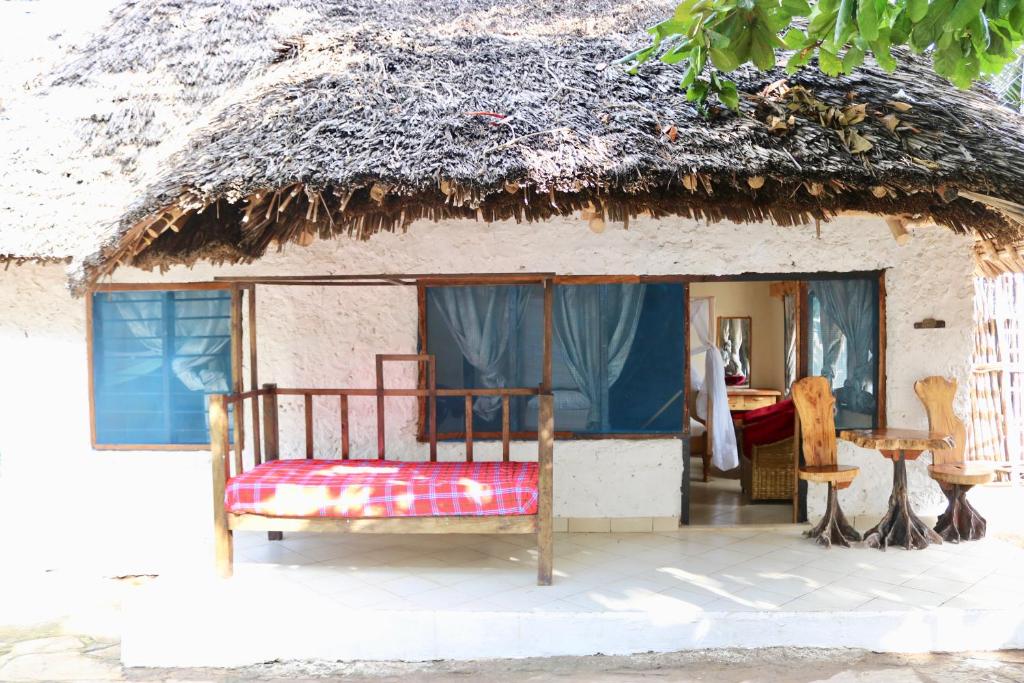 Bett vor einem strohgedeckten Haus in der Unterkunft Room in Guest room - A wonderful Beach property in Diani Beach Kenya - A dream holiday place in Mombasa
