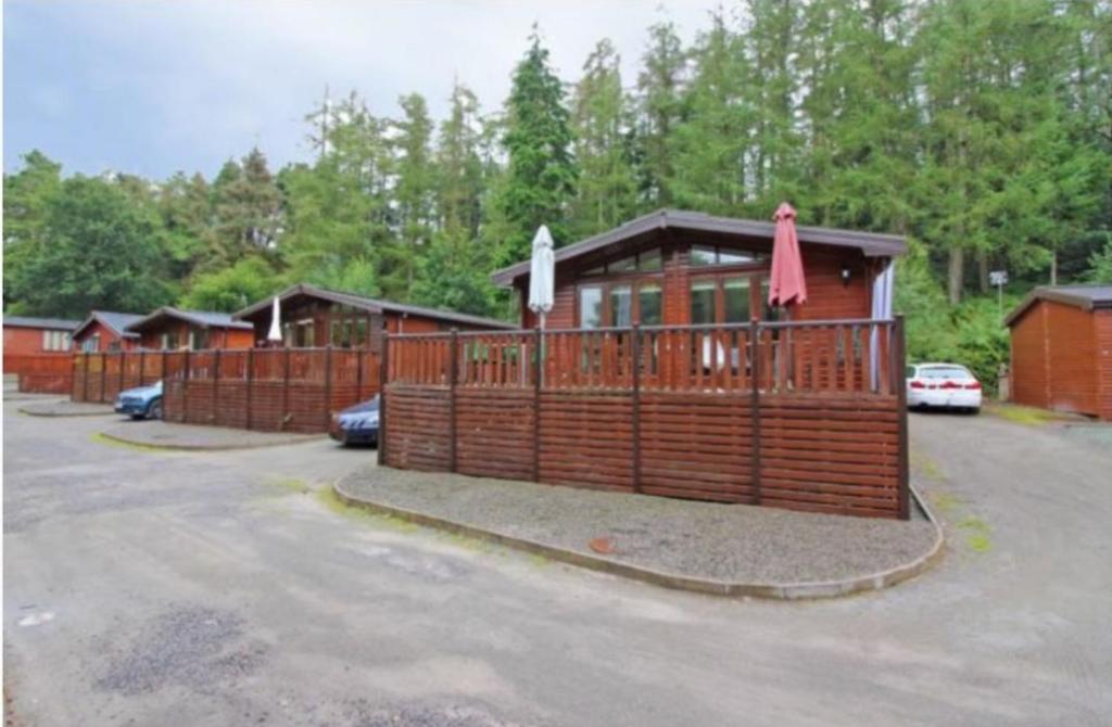 a wooden cabin with a gate in a parking lot at Astbury Falls Luxury Retreats in Eardington