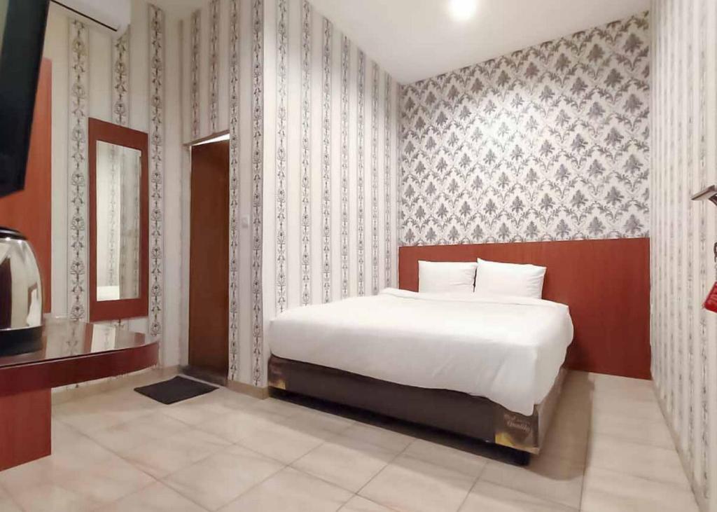 a bedroom with a white bed and a wall at RedDoorz Plus @ Jalan Letda Sujono Medan 2 in Pulauberayan Dadap
