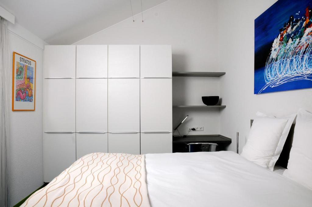 a bedroom with a white bed and a white cabinet at Domus Hotel in Luxembourg