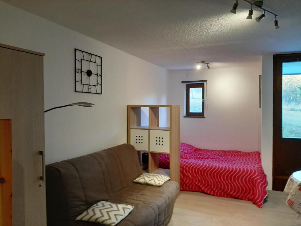 een woonkamer met een bank en een bed bij Studio rénové, calme avec Terrasse S-O, prestations de qualité - Résidence Les Adraits in Les Rousses