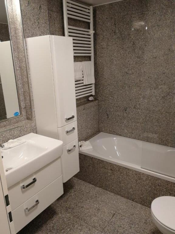 a bathroom with a sink and a tub and a toilet at Domus Hotel in Luxembourg