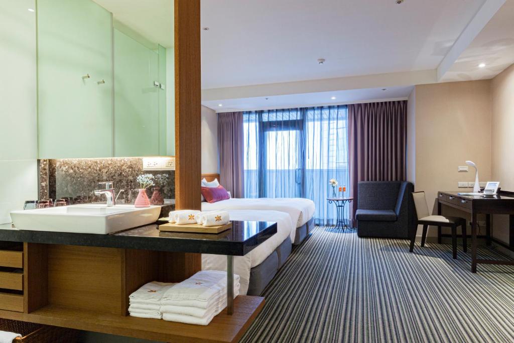 台北市にあるパシフィックビジネスホテルのベッド、洗面台、バスルームが備わるホテルルームです。