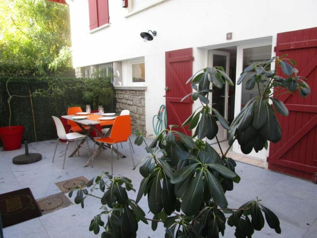 a house with a red door and a table and chairs at MAGNOLIAS 2- quartier résidentiel proche de la plage in Hendaye