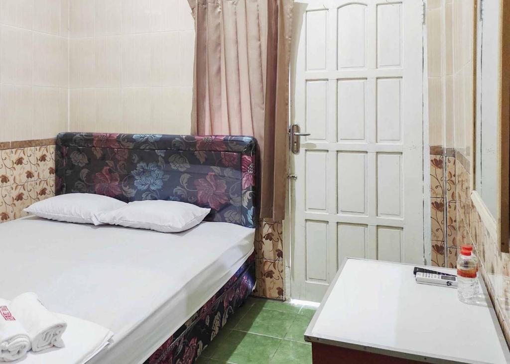 Schlafzimmer mit einem Bett, einer Tür und einem Tisch in der Unterkunft Queen Asri Mitra RedDoorz in Kediri