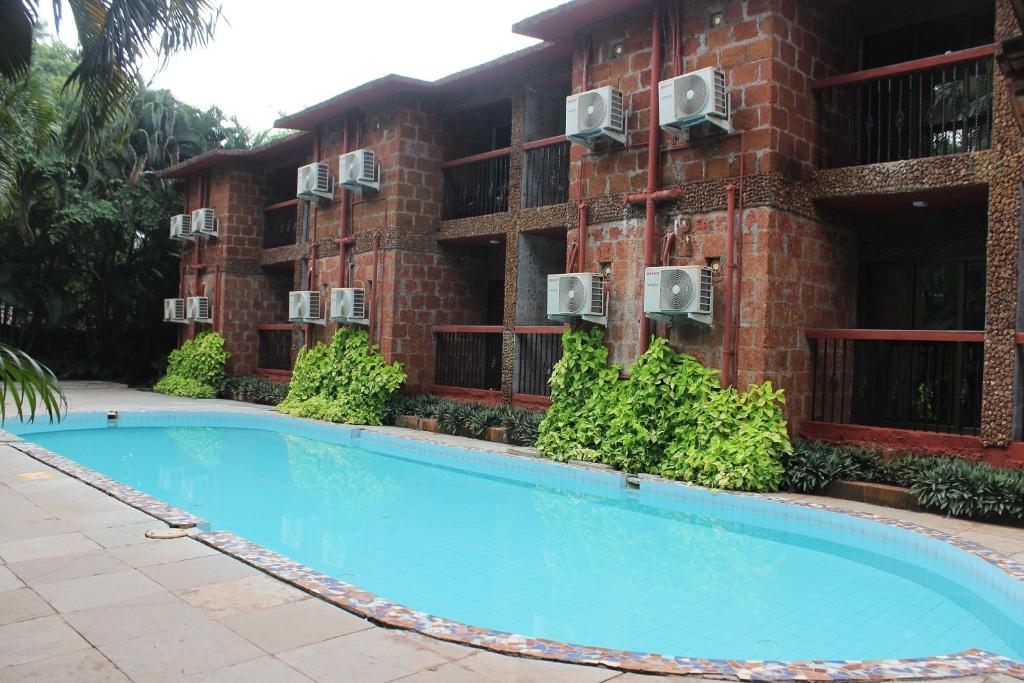 a building with a swimming pool in front of a building at Sea Breeze Inn, Calangute Goa in Calangute
