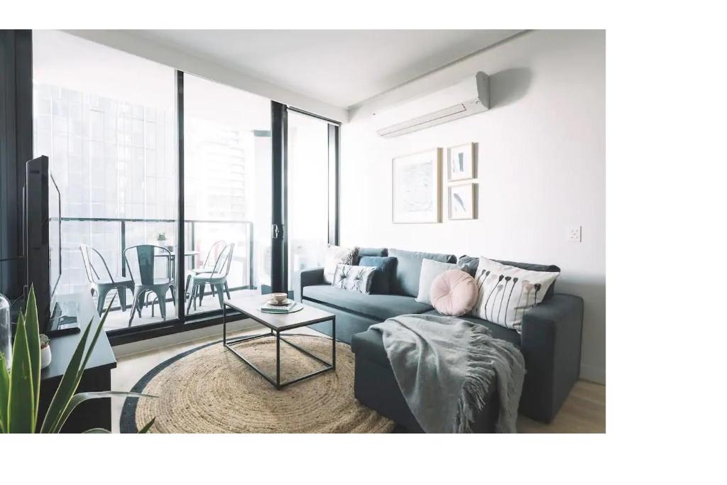 een woonkamer met een bank en een tafel bij 2 BR Modern Melbourne CBD Apartment in Melbourne