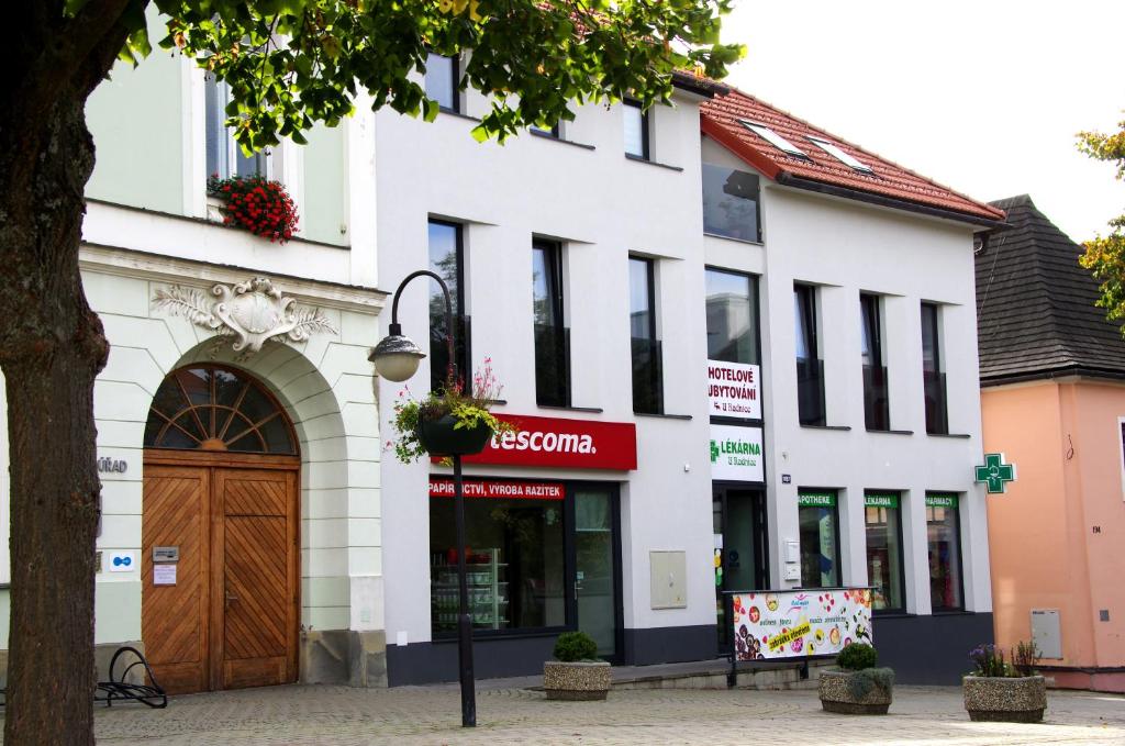 un edificio blanco con una puerta marrón en una calle en HOTELOVÉ UBYTOVÁNÍ U RADNICE en Valašské Klobouky