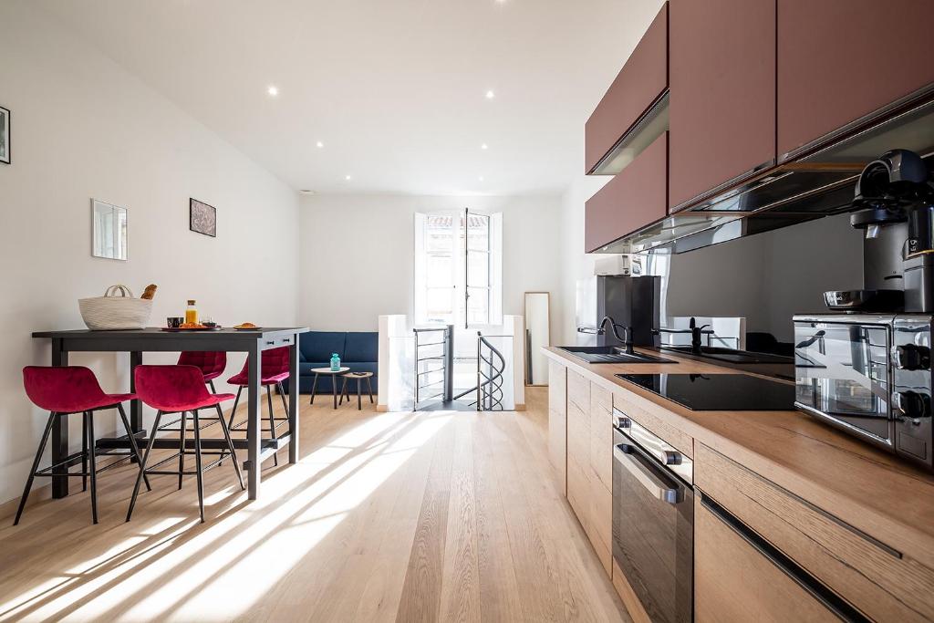 a kitchen with a table and red chairs in it at Mieuxqualhotel jacuzzi privatif Le carré in Bordeaux