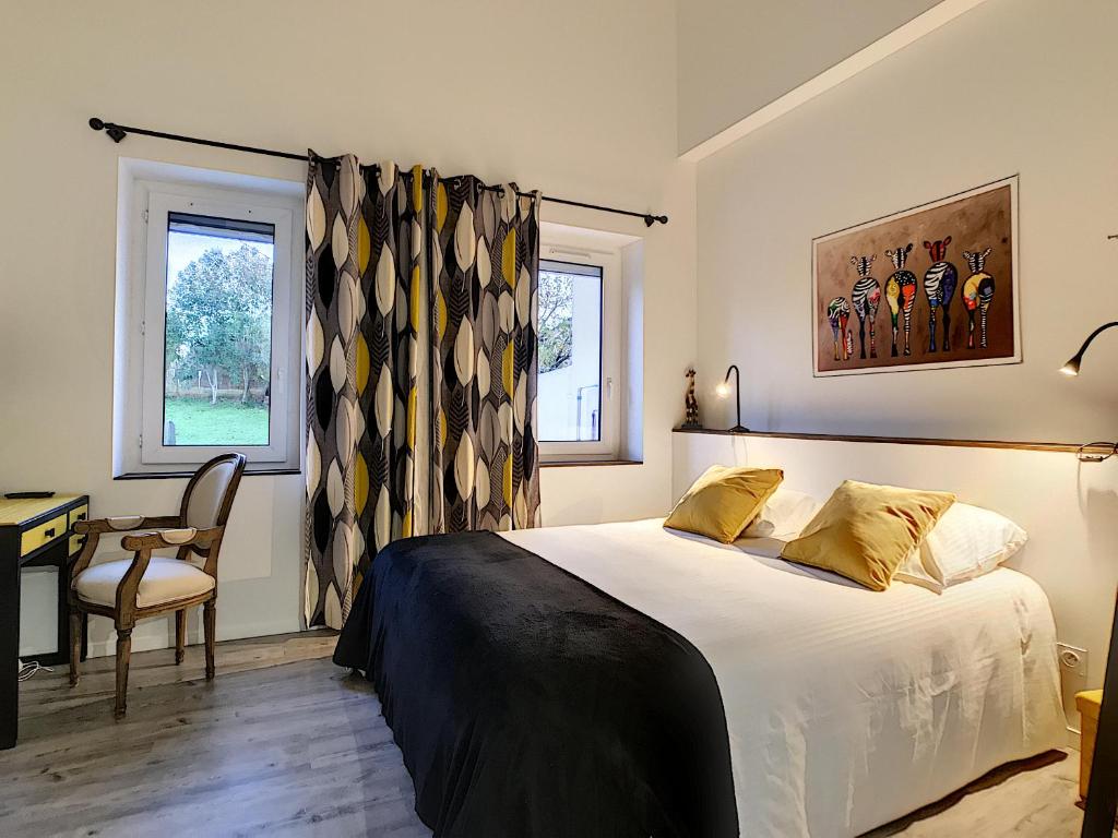 a bedroom with a bed and a desk and a chair at La ferme de Pham in Belberaud