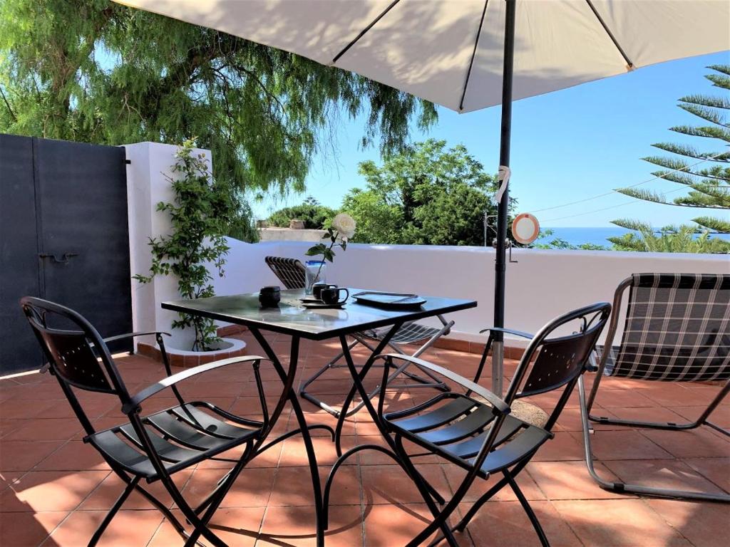 einen Tisch und Stühle auf einer Terrasse mit Sonnenschirm in der Unterkunft Casa Papuzza in Malfa