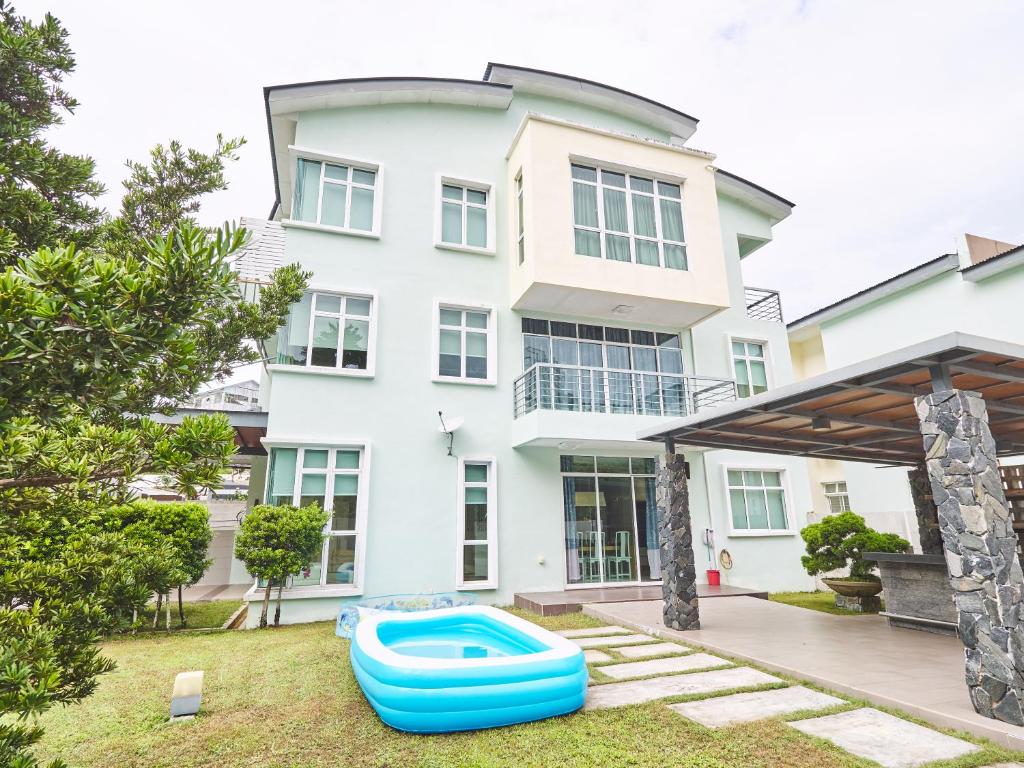 ein großes weißes Haus mit Pool im Hof in der Unterkunft Shamrock Villas Corner OR Seaview OR Standard in Batu Feringgi