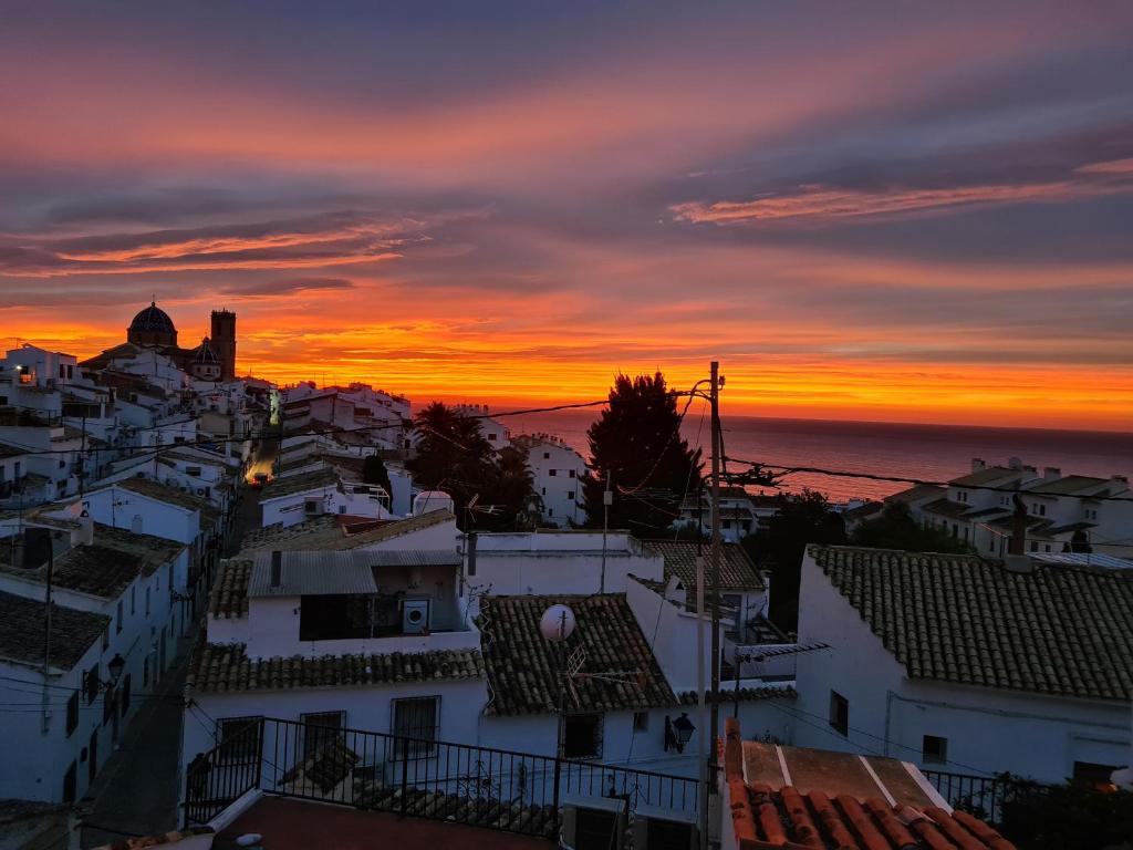 a sunset over the roofs of buildings in a city at Hostal Fornet Altea in Altea