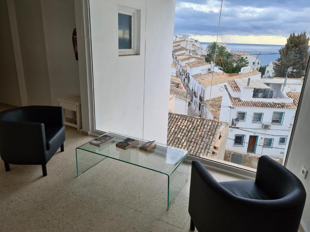 a room with two chairs and a glass table and a window at Hostal Fornet Altea in Altea