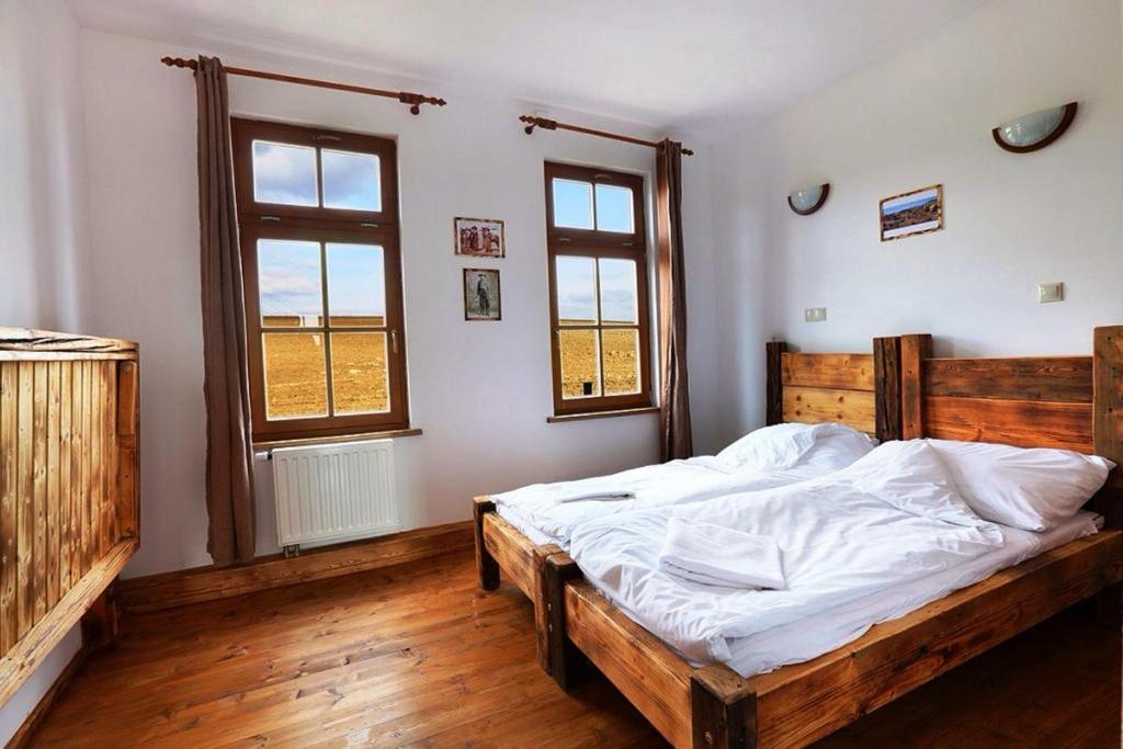 a bedroom with a bed with white sheets and two windows at Tordas Western House in Tordas