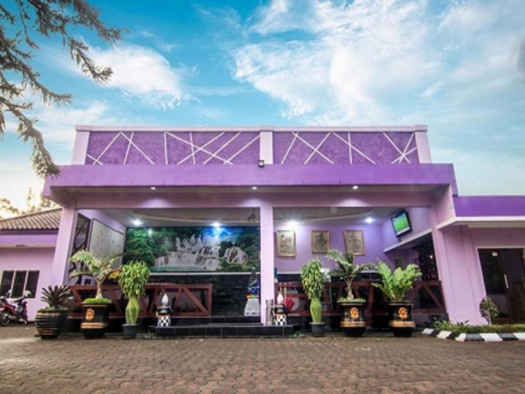 a pink house with a purple roof at Hotel Signature Mandala Kencana in Tjiandjur