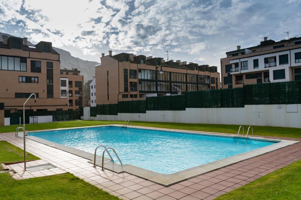 a large swimming pool in a city with buildings at La Caparina, apartamento con piscina a 3 km de la playa in Llanes