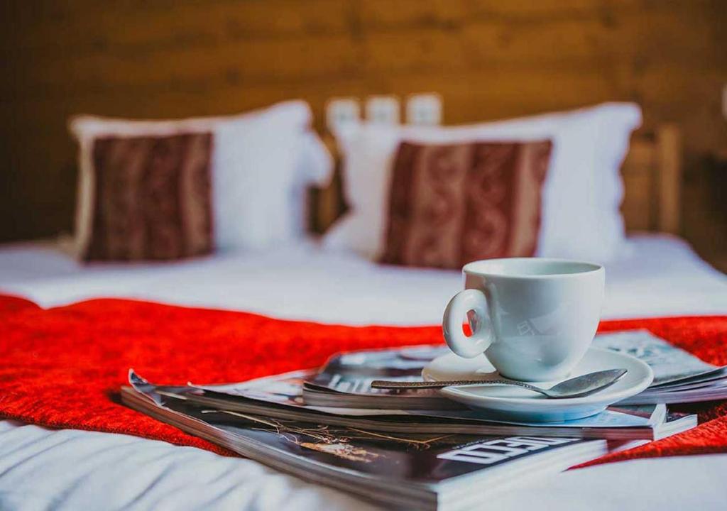 a table with a coffee cup and plates on a bed at Hôtel Les Grangettes in Méribel