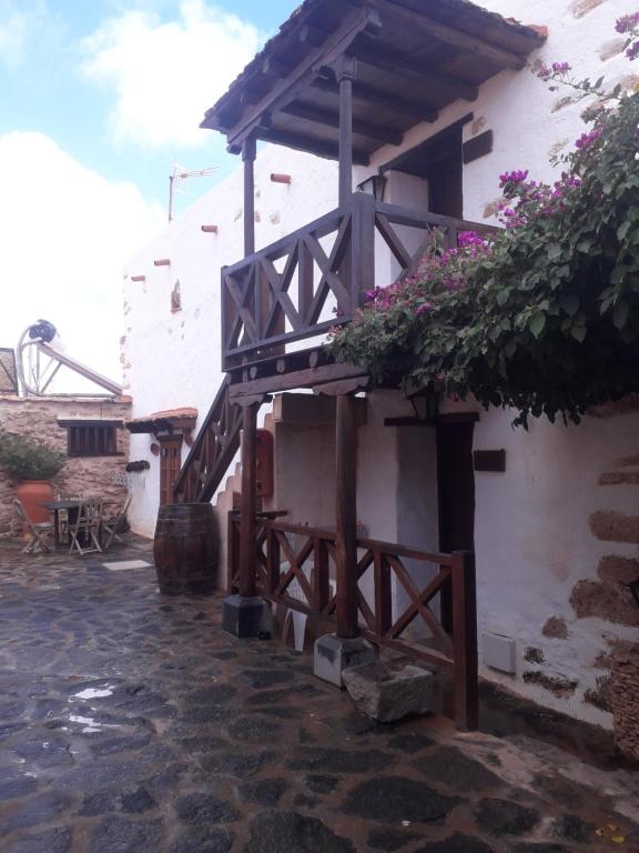 un edificio con un porche de madera con flores. en Casa Rural Tamasite en Tuineje