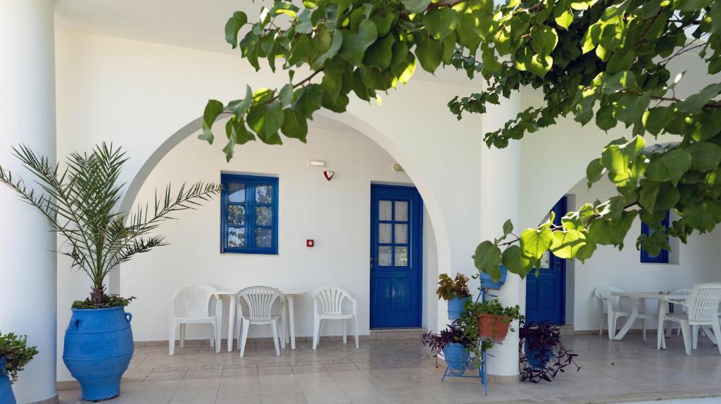 een kamer met blauwe deuren en tafels en stoelen bij Stegna-TULA in Archangelos
