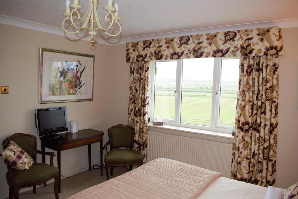 1 dormitorio con cama, ventana y escritorio en Parc Yr Odyn, en Pentraeth