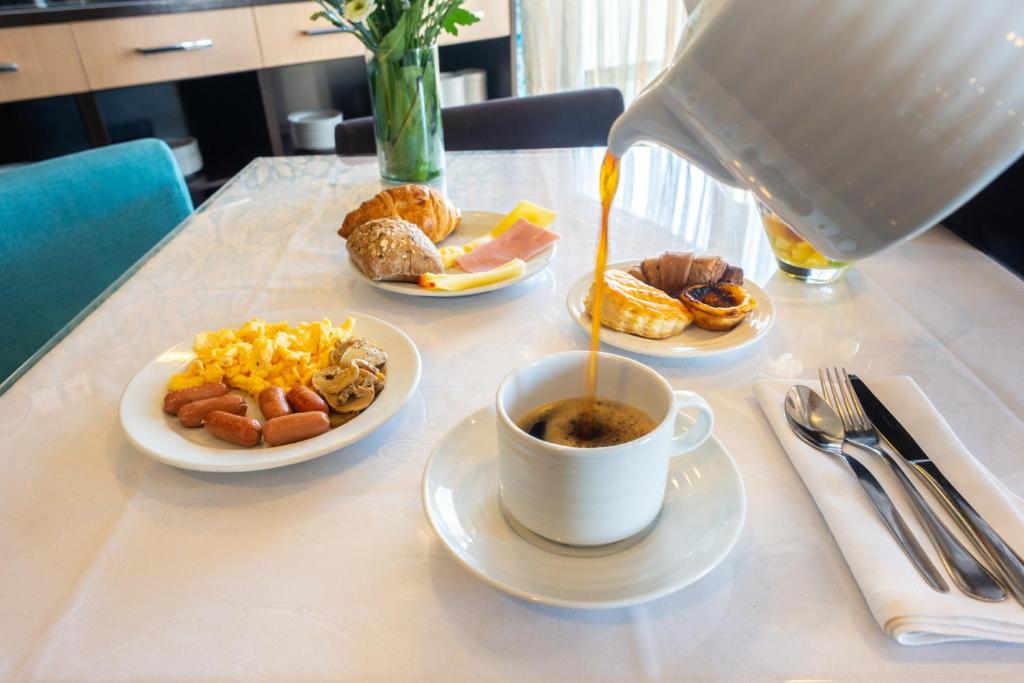 A plated breakfast with coffee, cooked items, pastries and orange juice.