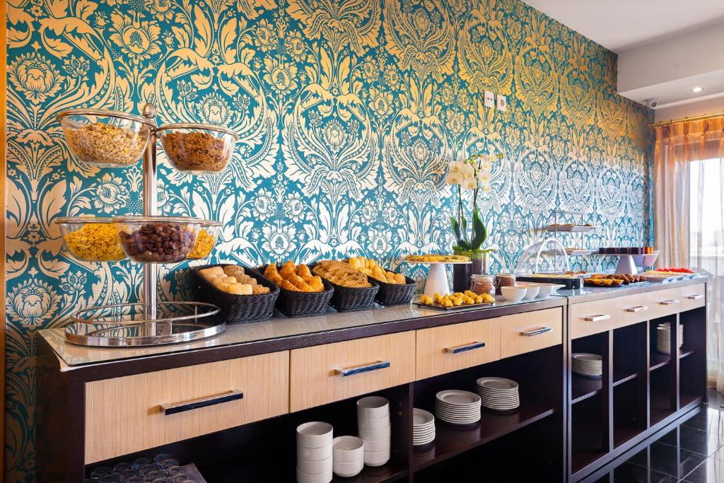 A bright breakfast buffet runs along a counter beside a curtained window.