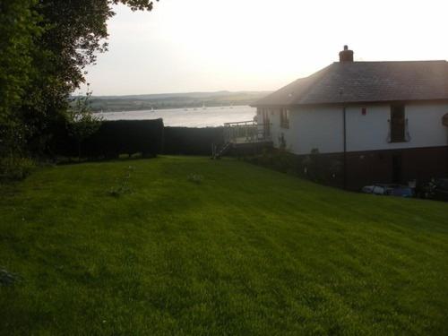 a yard of a house with a grassy yard next to a house at Riverdown in Topsham